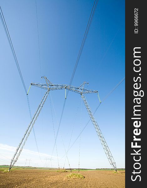 High voltage pylons on the background  of  blue  cloudless  sky