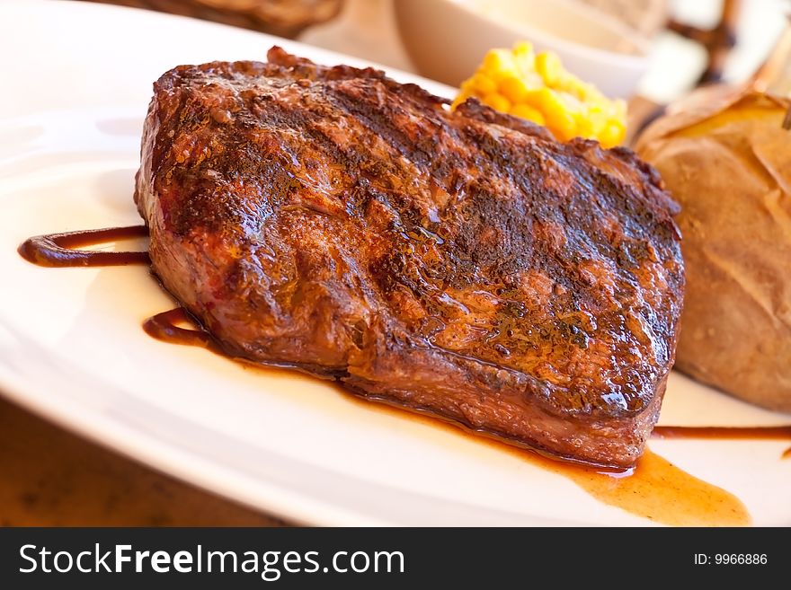 Sirloin strip steak with corn cob ,vegetables and savory sauce.