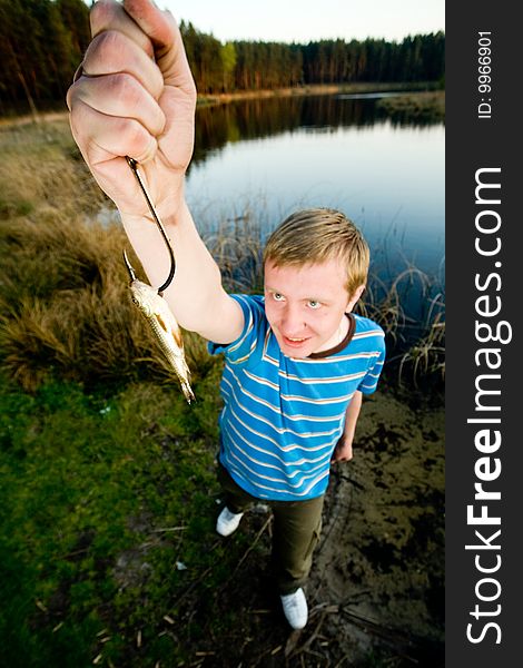A cute guy showing off a crucian he has just caught. A cute guy showing off a crucian he has just caught