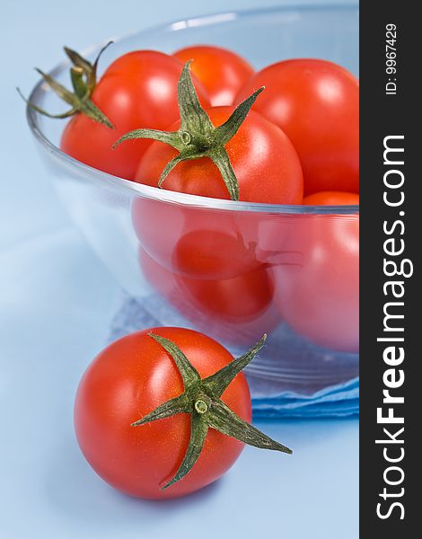 Cherry tomatoes in a glass on blue background. Cherry tomatoes in a glass on blue background