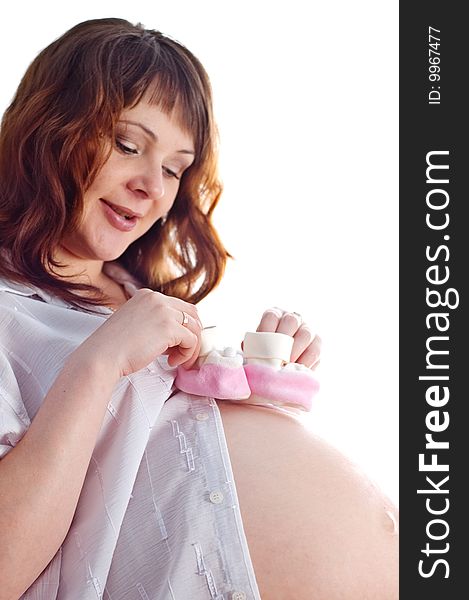 Close-up portrait of the smiling pregnant woman on the isolated background with small baby footwear. Close-up portrait of the smiling pregnant woman on the isolated background with small baby footwear