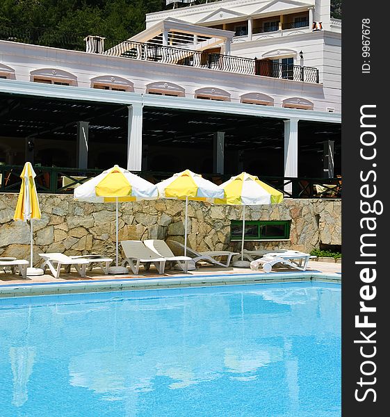 Sunbeds and umbrellas near resort's pool. Sunbeds and umbrellas near resort's pool
