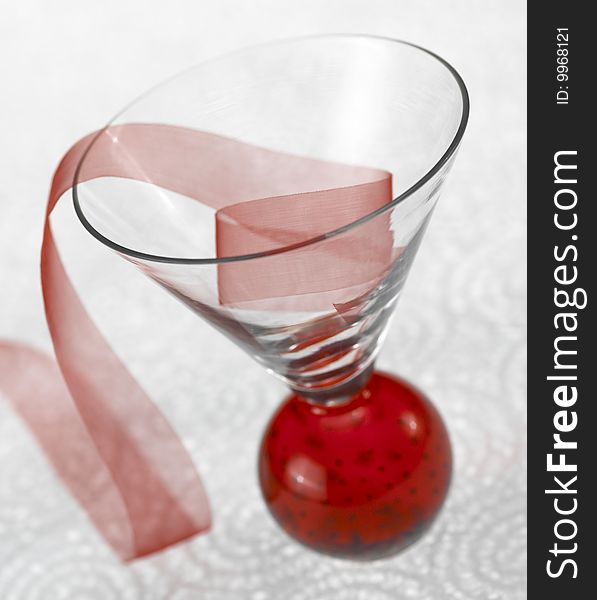 Red ribbon in glass cup on white plex