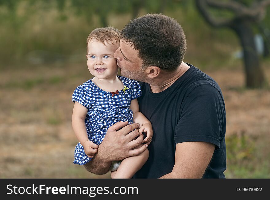 Father is holding his beautiful baby with eyes blue. Father and daughter playing outdoors. Smiling. Father is holding his beautiful baby with eyes blue. Father and daughter playing outdoors. Smiling