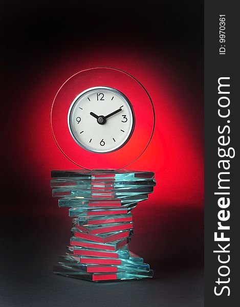 Modern glass clock with cool red glow background.