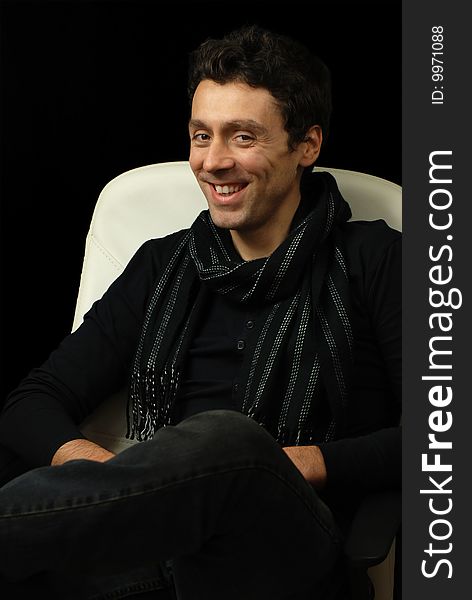 Man in a scarf sits back in his chair smiling. Man in a scarf sits back in his chair smiling.