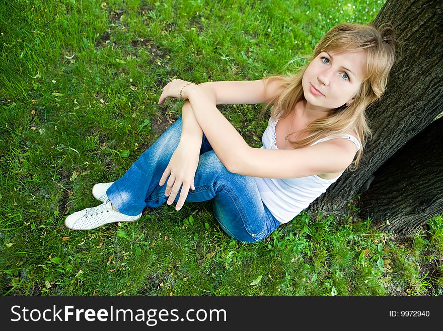 Beautiful young woman sits on a green grass. Beautiful young woman sits on a green grass