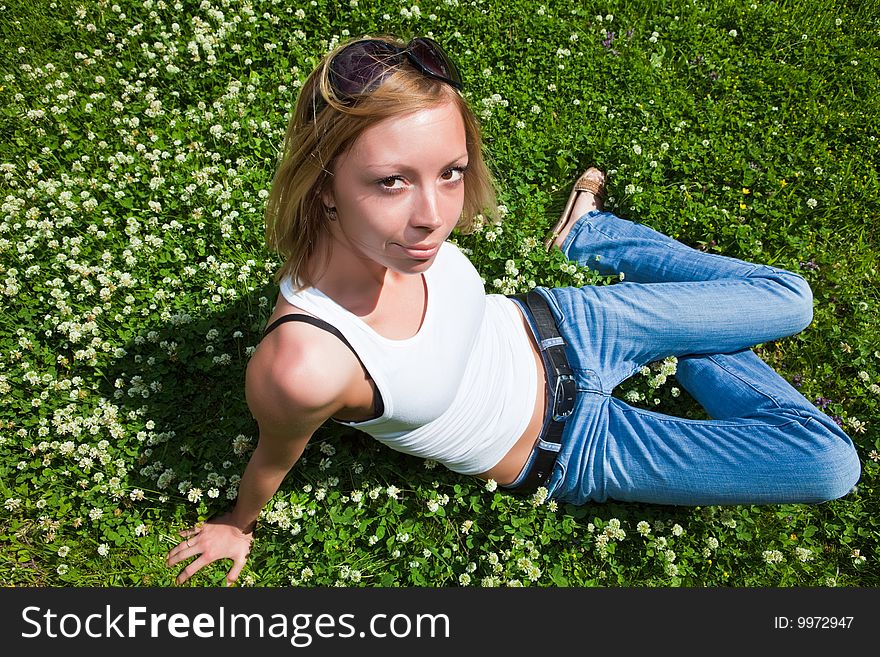 Beautiful young woman sits on a green grass. Beautiful young woman sits on a green grass