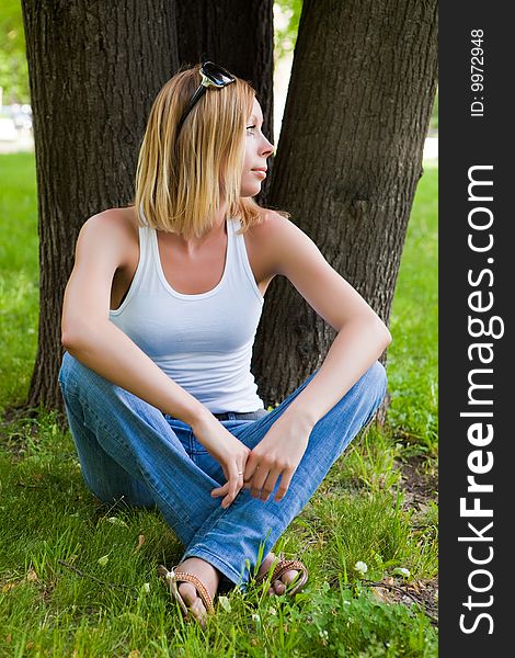 Beautiful young woman sits on a green grass. Beautiful young woman sits on a green grass