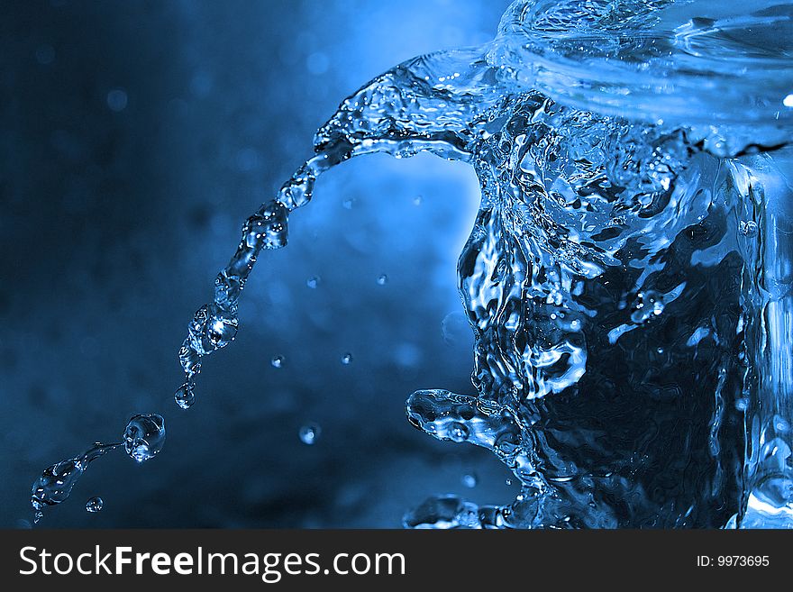 The shot of water splashing and blue drops. The shot of water splashing and blue drops