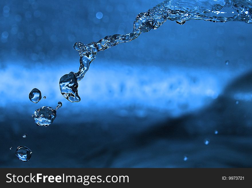 The shot of water splashing and blue drops. The shot of water splashing and blue drops