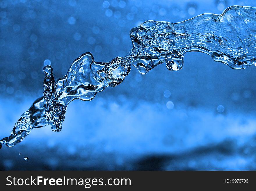 The shot of water splashing and blue drops. The shot of water splashing and blue drops