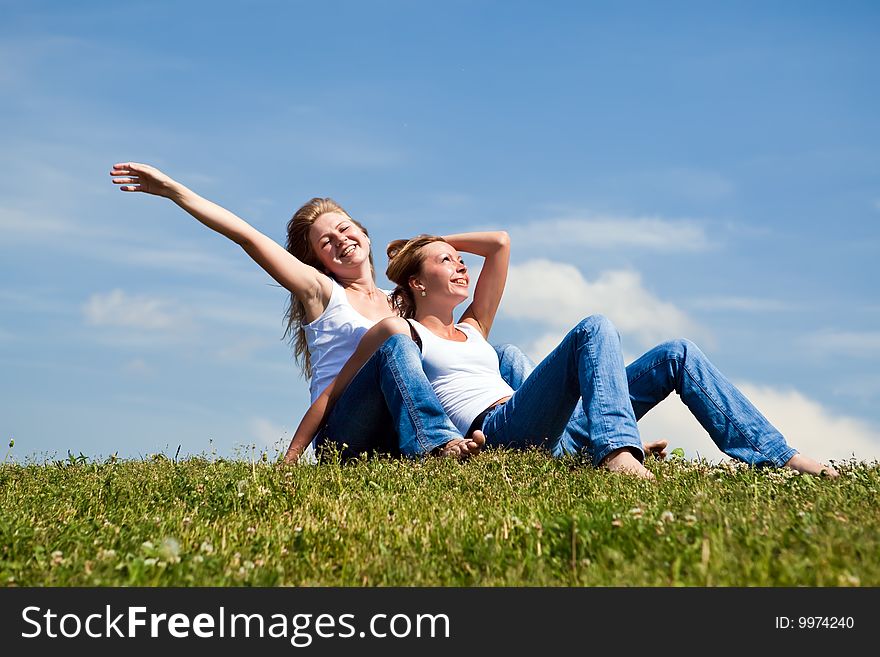 Two girls have a rest on a green grass. Two girls have a rest on a green grass