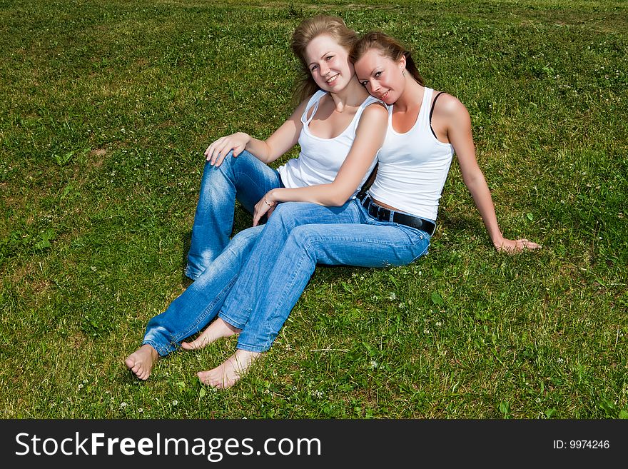 Two girls have a rest on a green grass