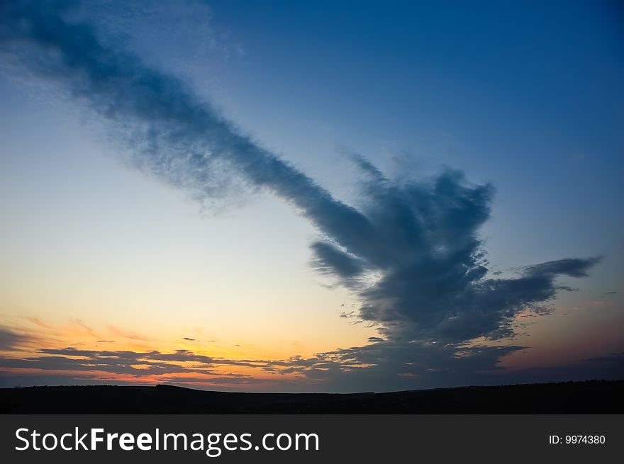 Dramatic sunset with strange cloud over dark horizon