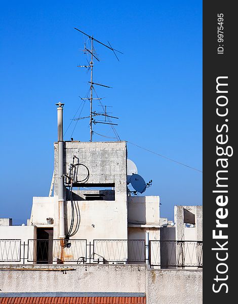 Old television aerial on house roof against blue sky