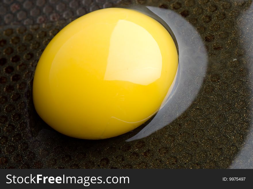 Broken egg on a black frying pan. closeup