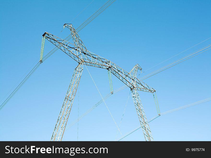 High voltage pylons on the background  of  blue  cloudless  sky