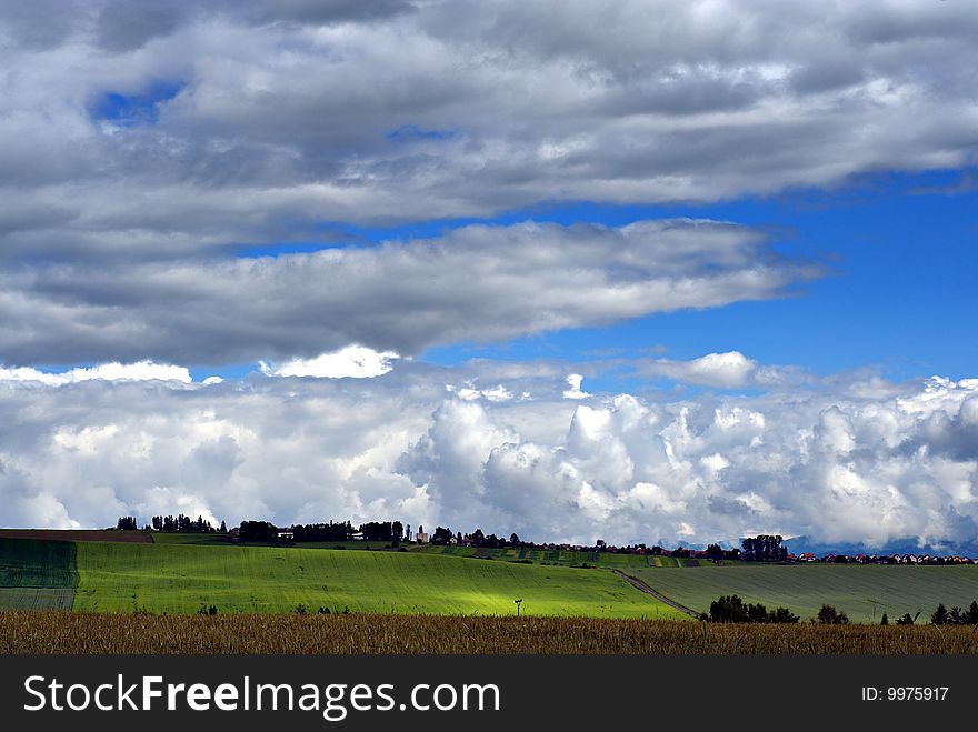 A village on horizon in summer day with fields and cloudy sky. A village on horizon in summer day with fields and cloudy sky