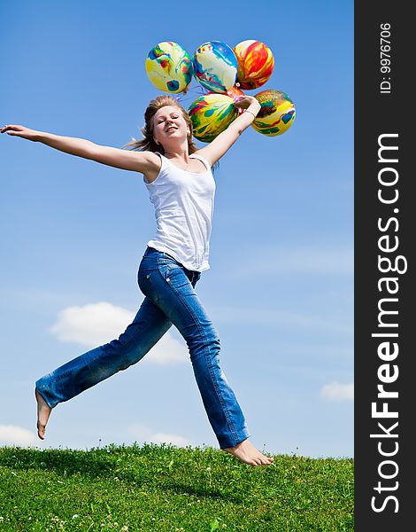Girl jumps on a green grass with balloons in a hand. Girl jumps on a green grass with balloons in a hand