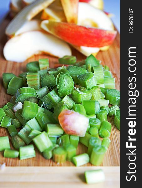 Red apple and green rhubarb cut for compote or jam cooking on a wooden kitchen board. Red apple and green rhubarb cut for compote or jam cooking on a wooden kitchen board