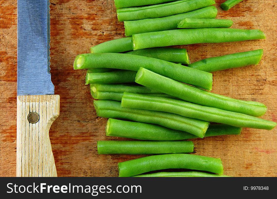 Fresh cut green beans and a knife on a rustic wooden table. Fresh cut green beans and a knife on a rustic wooden table.