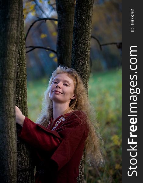 The blonde girl in medieval red dress in the autumn forest. The blonde girl in medieval red dress in the autumn forest