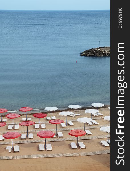 Empty beach with many sunbeds and parasols.