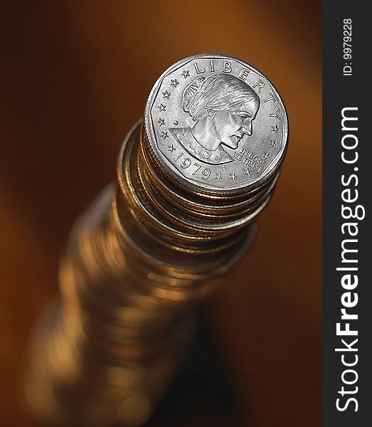 Overhead view of tall stack of balancing coins, dark brown background. Overhead view of tall stack of balancing coins, dark brown background.