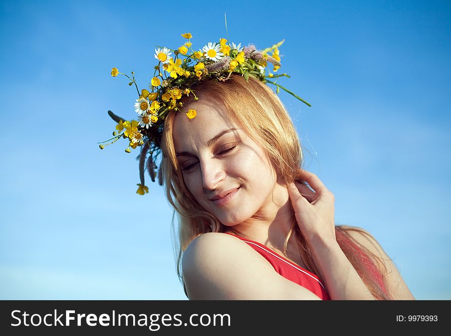 A nice woman in a chaplet of yellow flowers and chamomiles