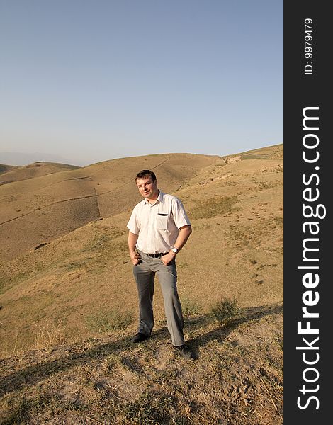 The tourist poses on a hills background in Tadjikistan. The tourist poses on a hills background in Tadjikistan