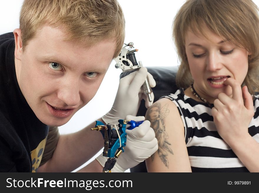 An image of man making tattoo on woman shoulder. An image of man making tattoo on woman shoulder