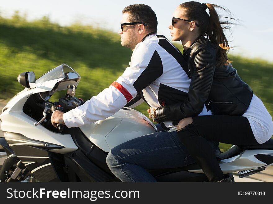 Young men and a women on a motorcycle by day. Young men and a women on a motorcycle by day