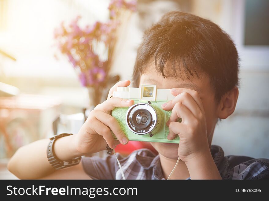 Boy taking photo by classic camera with vintage filt