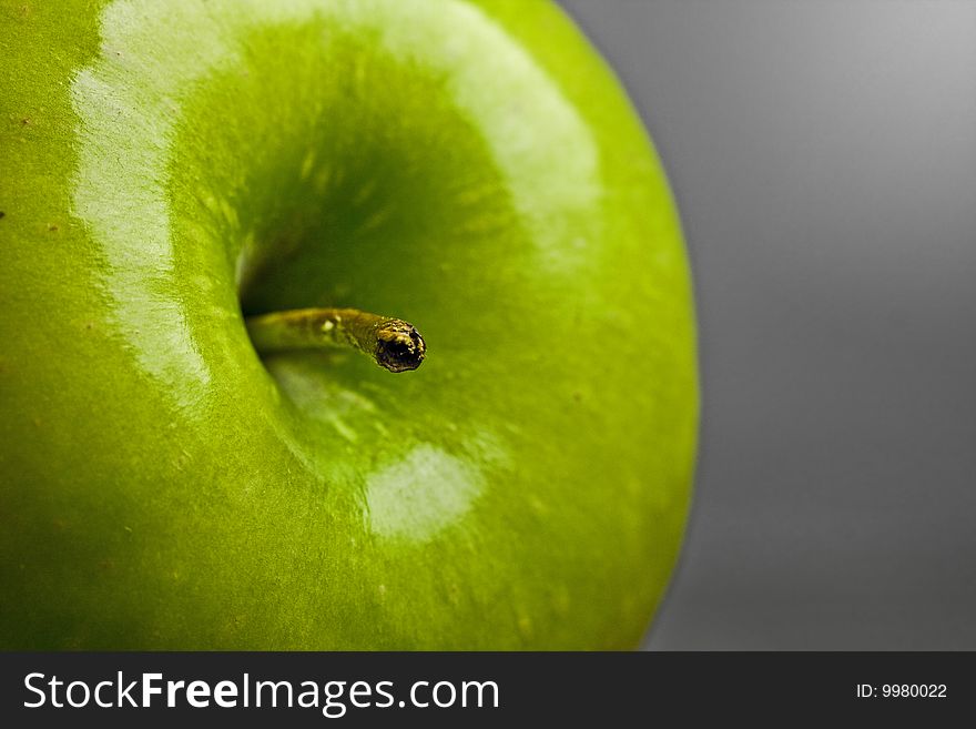 Close up shot of a delicious shiny green apple against a green background. Close up shot of a delicious shiny green apple against a green background