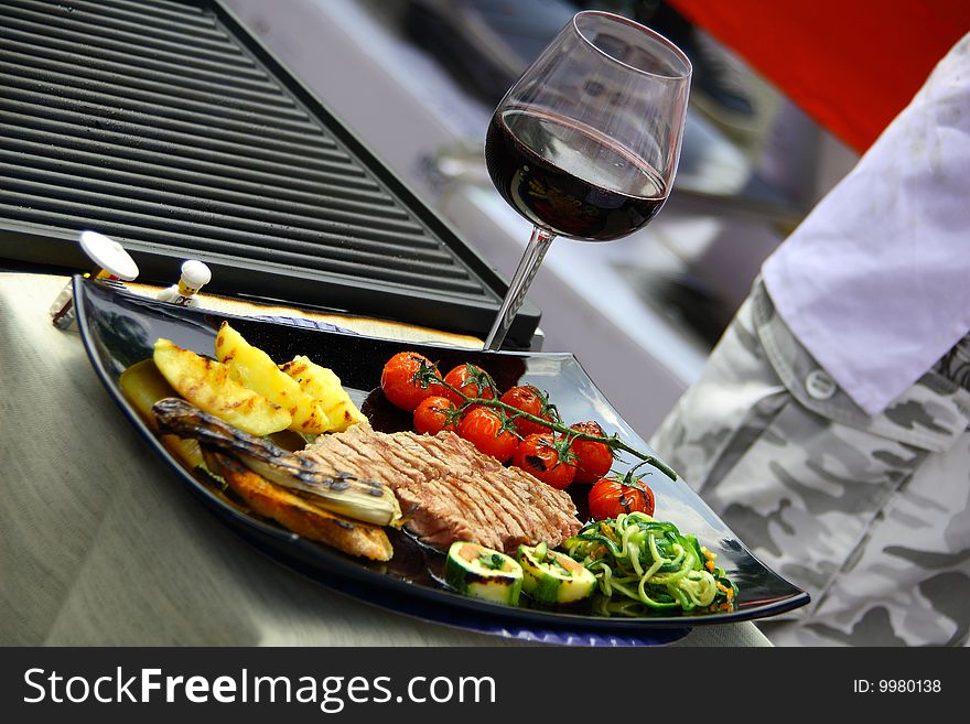 Dish consisting of meat and mixed grilled vegetables and a glass of red wine