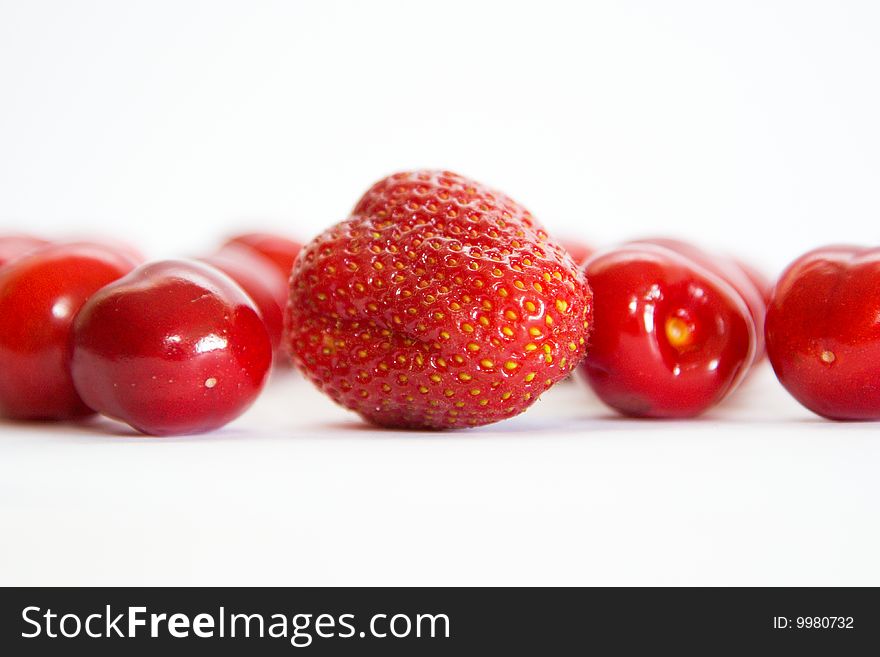 Separate berries of a sweet cherry abreast and one berry of the Strawberry