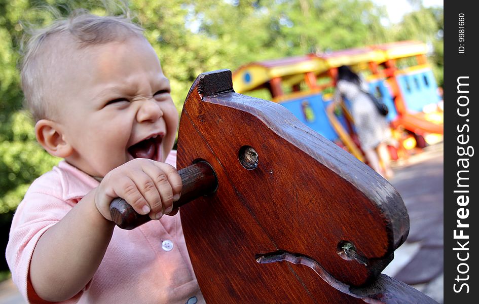 A motion blurred portrait of a happy child (16 months young) on a wooden horse swing. A motion blurred portrait of a happy child (16 months young) on a wooden horse swing