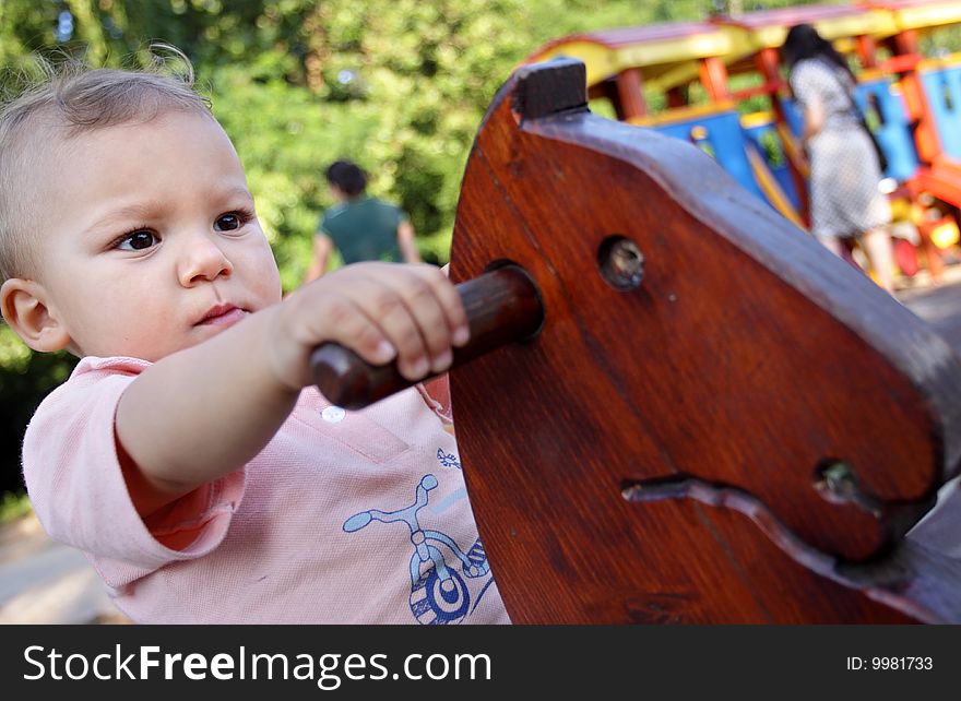 A portrait of a seriously looking child (16 months young) on a wooden horse swing. A portrait of a seriously looking child (16 months young) on a wooden horse swing