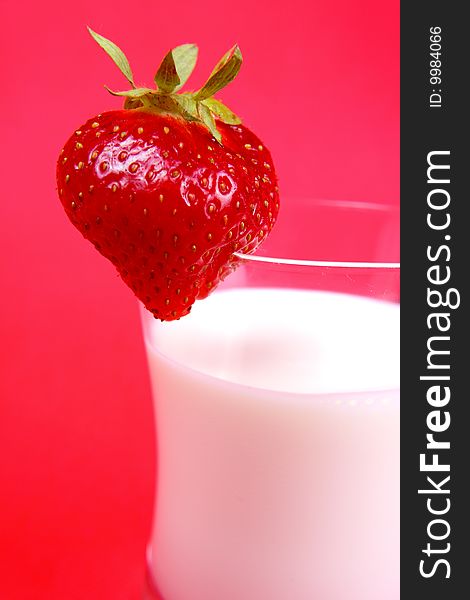 Photo of milk drink with strawberry on red background. Photo of milk drink with strawberry on red background