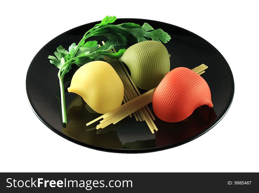 Pasta of different colors and forms on black plate