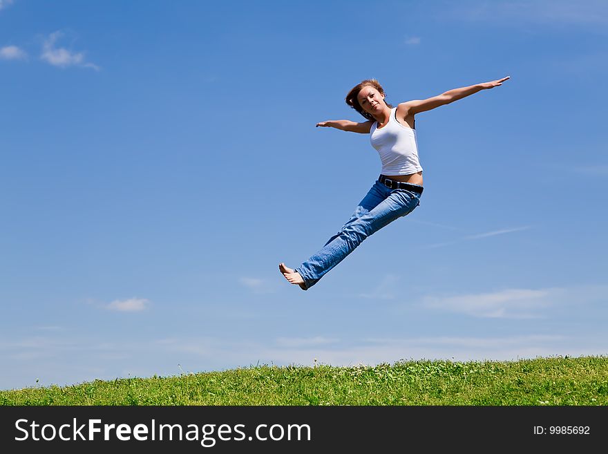 Girl jump on a green grass against the blue sky. Girl jump on a green grass against the blue sky