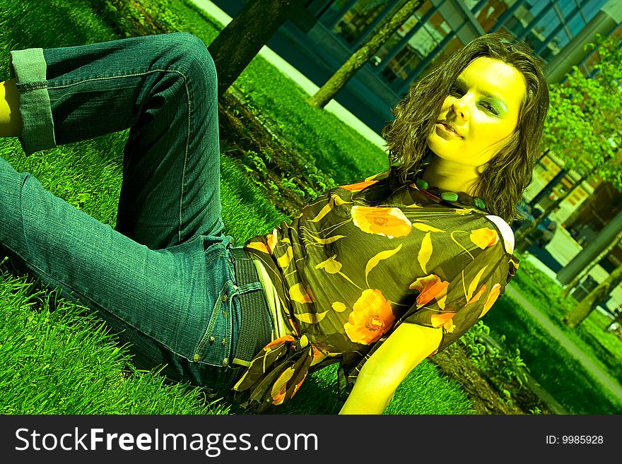 Teenage girl sitting in a park on the grass under the noon sun. Teenage girl sitting in a park on the grass under the noon sun