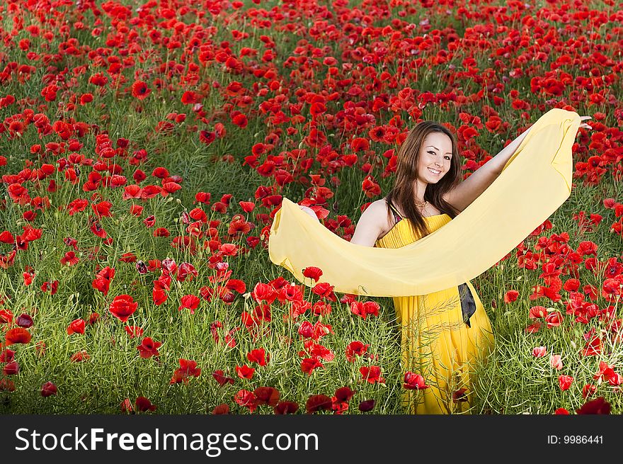 Beautiful smiling girl with yellow scarf in the poppy field