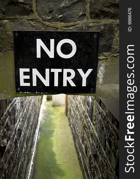 Clear sign at narrow pathway with stone walls. Clear sign at narrow pathway with stone walls