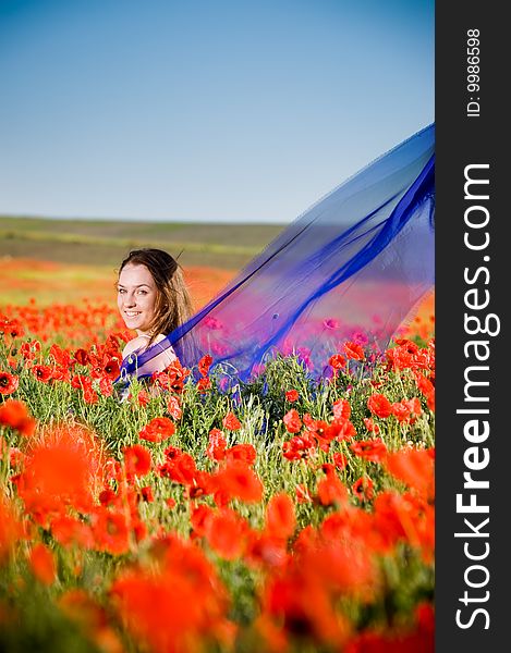 Smiling girl with blue scarf in the poppy field. Smiling girl with blue scarf in the poppy field