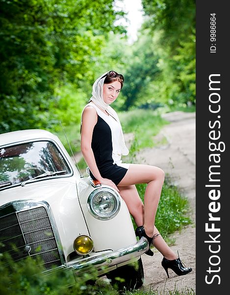 Beautiful pin-up styled girl sitting on retro car