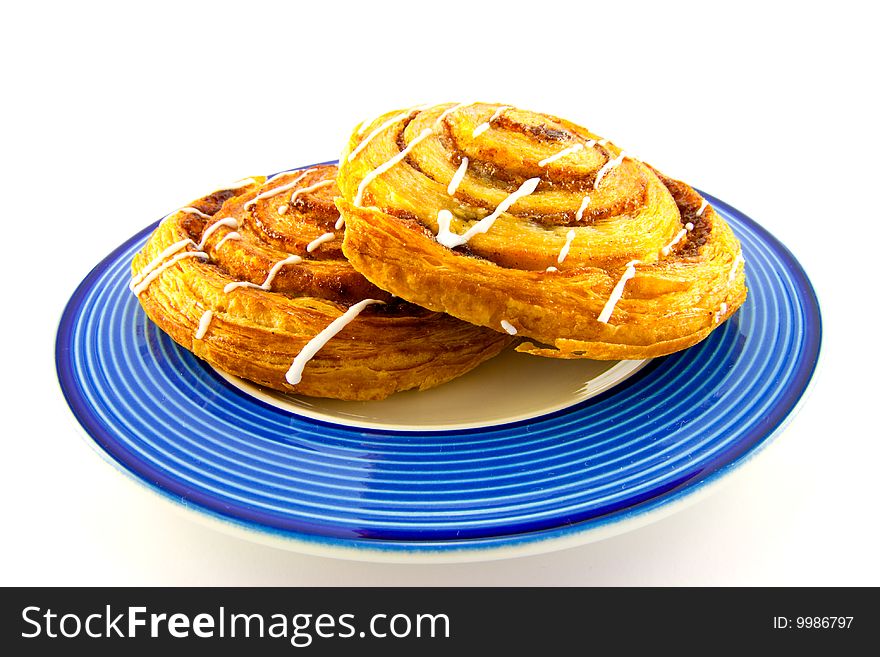 Two cinnamon buns on a blue plate with clipping path on a white background