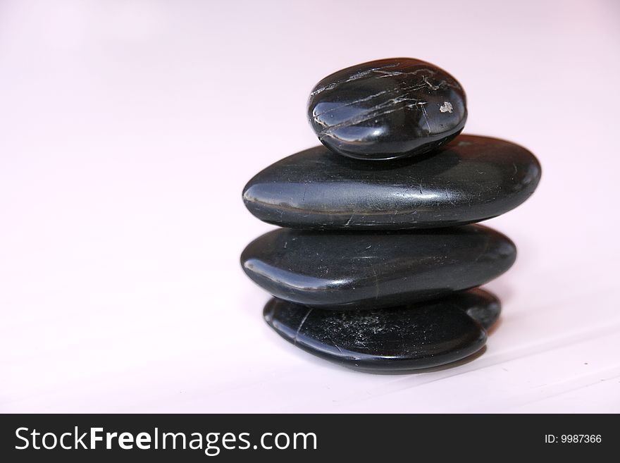 An image of shiny black stones over soft pink pale background