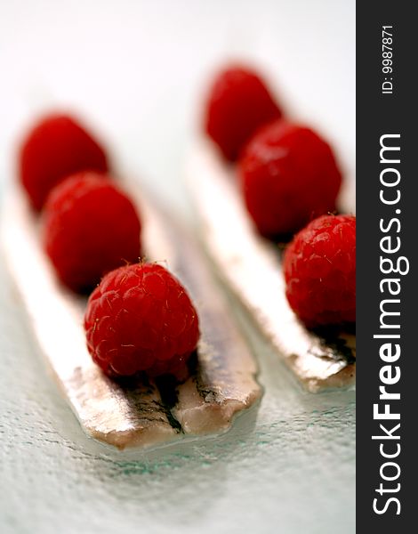 Fillets of anchovies with raspberries on a glass plate. Fillets of anchovies with raspberries on a glass plate